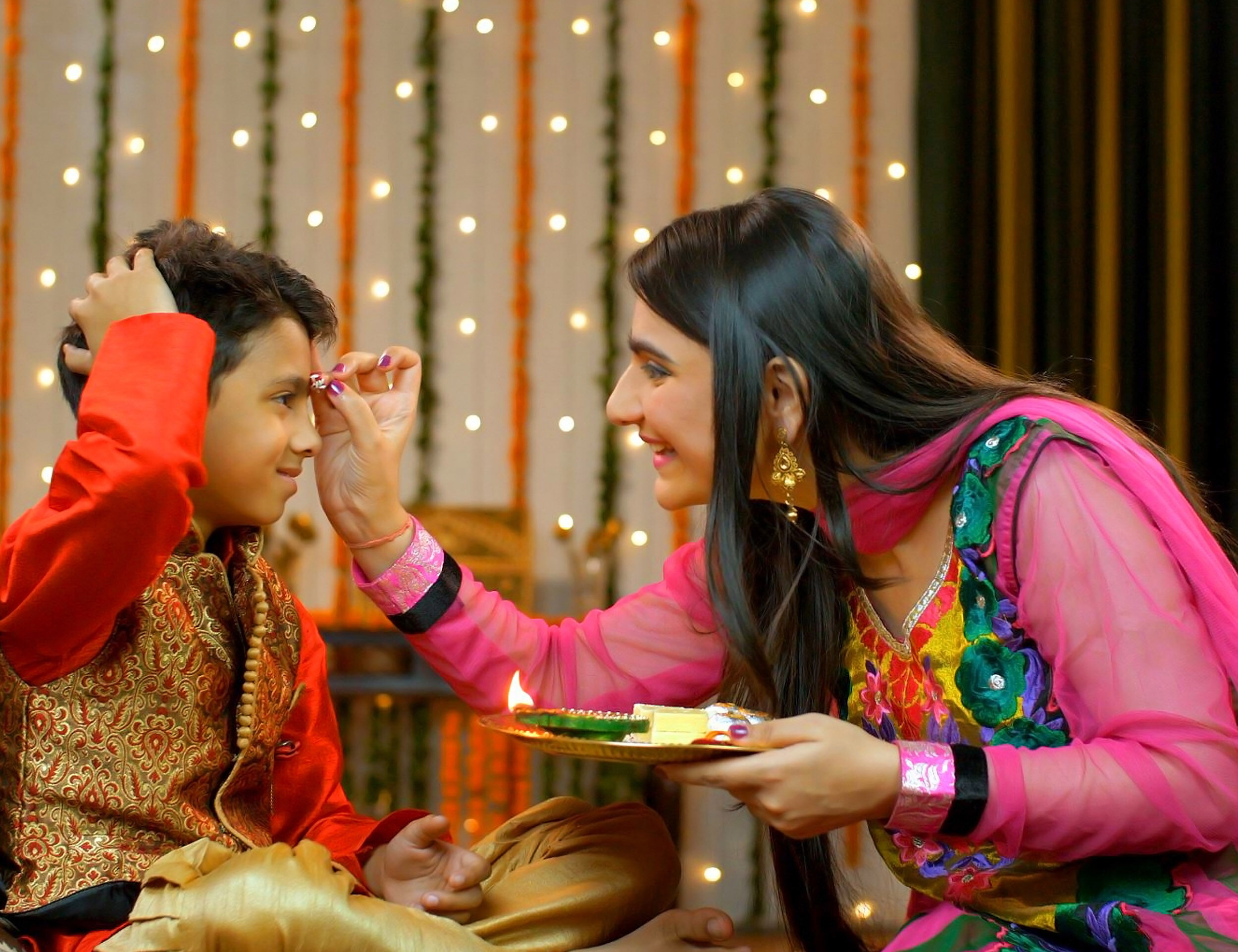 Sister performing the essential tika ceremony ritual on her brother's forehead for the Bhai Dooj festival.